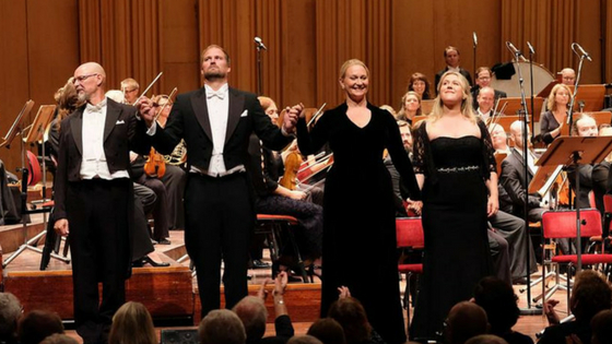 People on stage in front of a orchestra