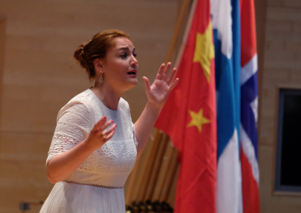 Woman singing with flags in the background